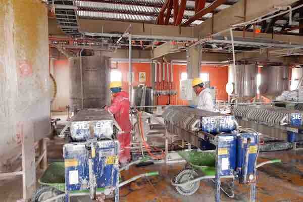 Two workers labor in an industrial site