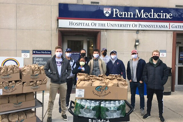 Members of the sprint football team stand outside of HUP with bags of food and bottles of water.