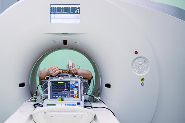 Person inside an MRI machine hooked up to a machine via a monitor on the finger.