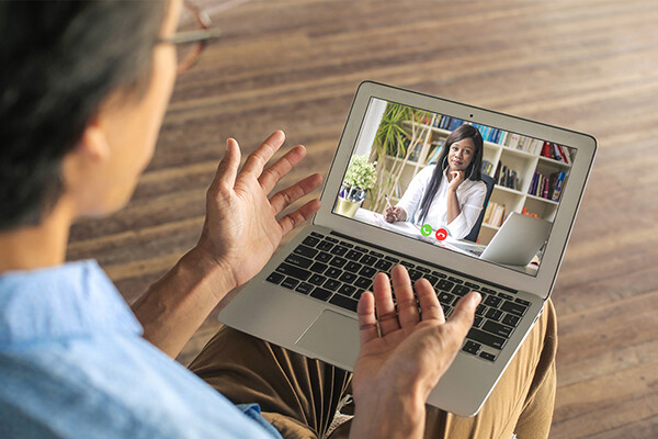 Person with a laptop on their lap talking with a doctor via telemedicine portal.