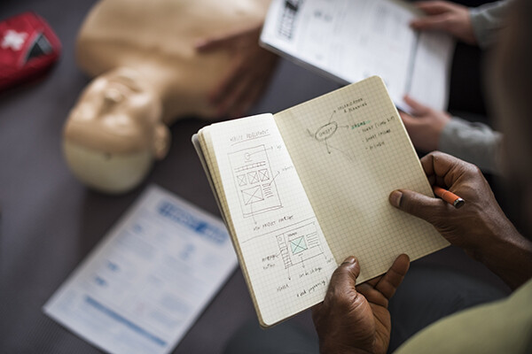 Person holding a sketchbook over a table with a human anatomy dummy.
