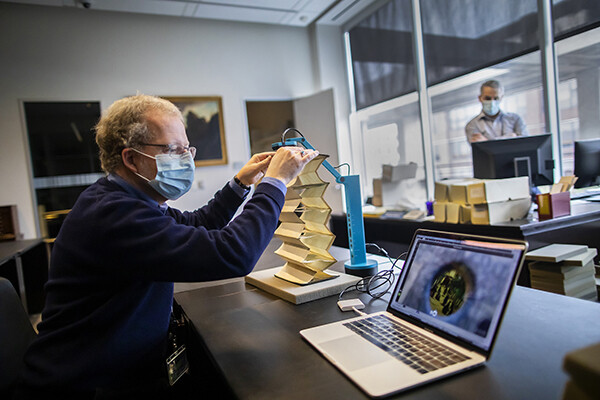 John Pollack uses a document camera to scan a pop-up book from the Kislak Center onto a laptop on a table he is seated at. 