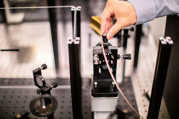 a hand adjusting a lens on an optics table