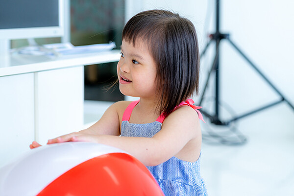 Young child with autism plays with a large beach ball.