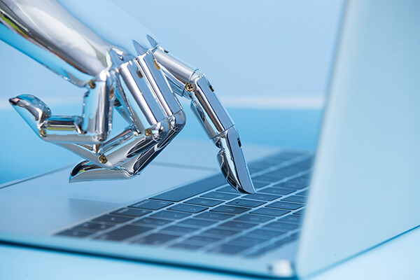 Robotic finger pressing a computer key on a laptop.