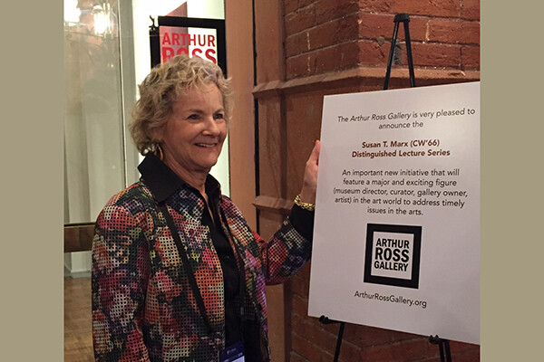 Susan T. Marx smiling in front of a sign in the Arthur Ross Gallery that reads Susan T. Marx Distinguished Lecture Series/Arthur Ross Gallery.