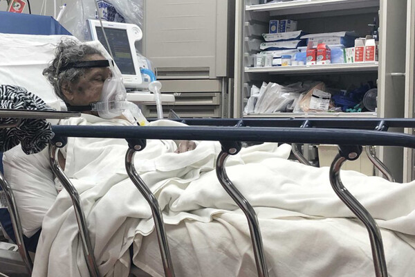African American COVID patient wearing a respirator in a hospital bed.