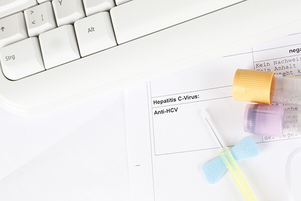 hep c lab paperwork and sample vials next to a computer keyboard.