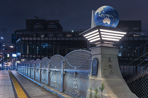 Globe and athletes sculptures on bridge