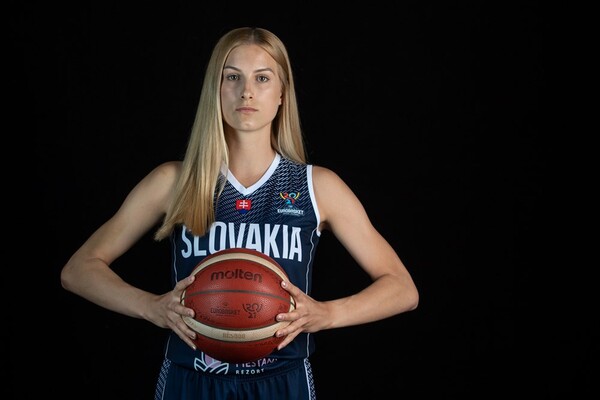 Nikola Kovacikova holds a basketball while wearing her Slovakia women's basketball team uniform, against a black background.