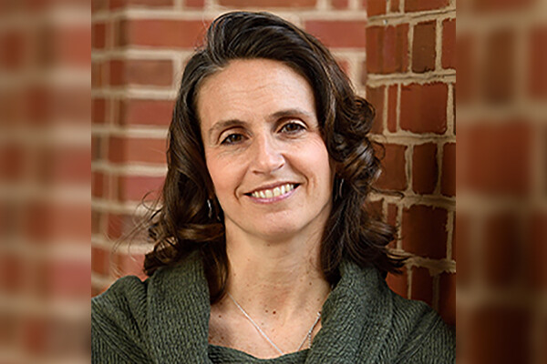 Alana Shanahan headshot against a brick wall background.