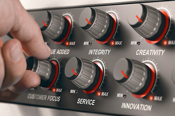 Hand  turning a button on a dashboard with all core values of a company to set it to the maximum.