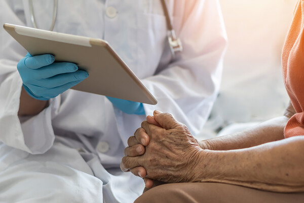 Person sitting with doctor who is showing them something on a tablet.