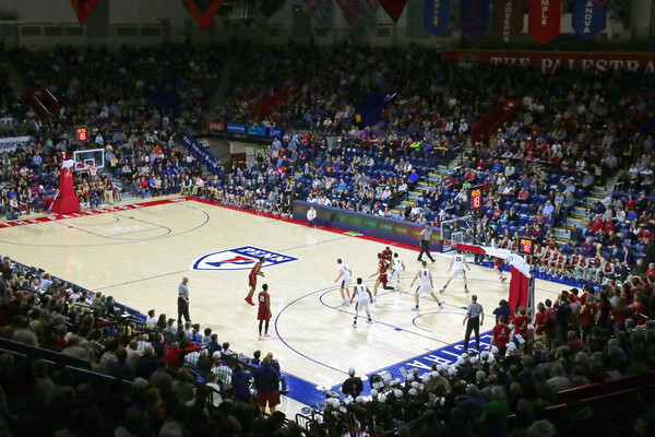 Wearing their white jerseys, Penn's men's basketball team plays a home game at the Palestra in front of a packed crowd.