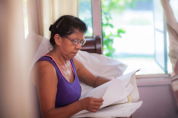 Middle-aged person sitting on couch looking over paperwork.