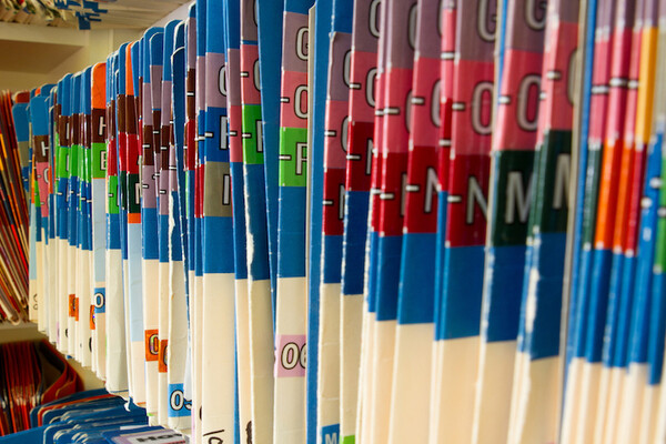 Folders full of alphabetized medical records on a shelf.