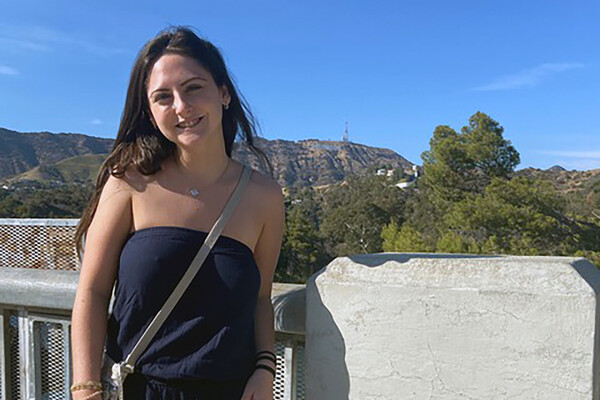 student standing outside with hill in the background