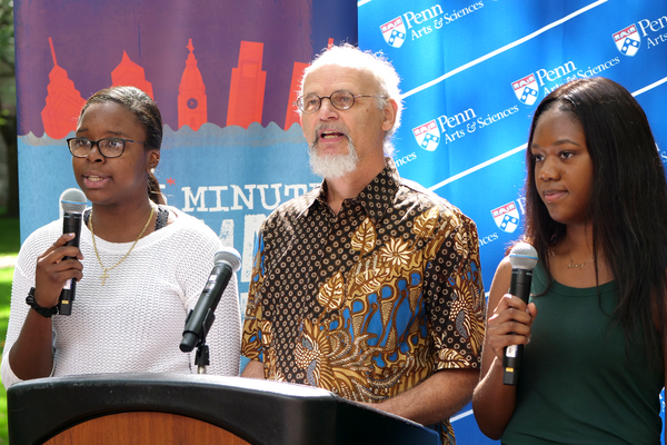 Three people speak at a lecturn outside