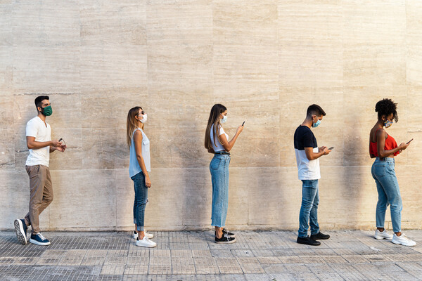 people standing outside in a line wearing masks