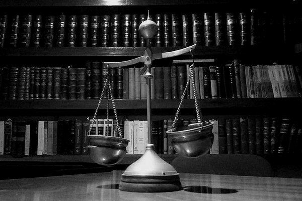 A close up to the an ornamental scale in an office with law books on shelves behind it.