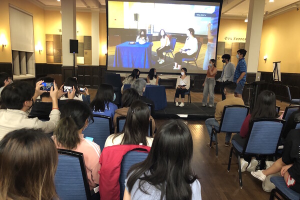 A group of students watch student chefs present a meal onstage