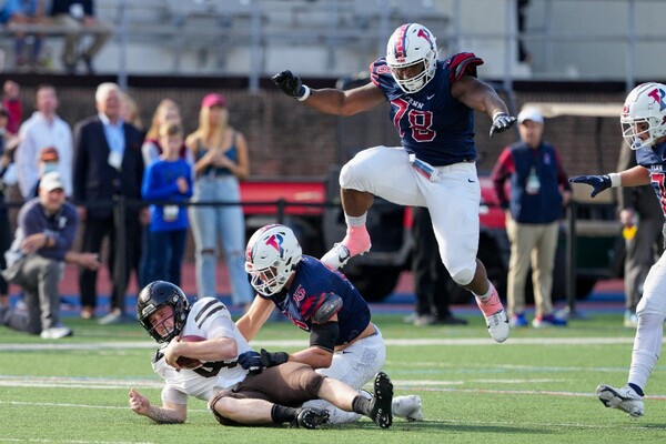 At Franklin field, senior linebacker Jake Heimlicher sacks the quarterback while senior defensive lineman Prince Emili leaps in the air.