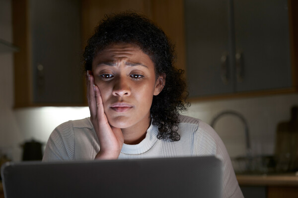 Person looking at laptop computer, visibly concerned.