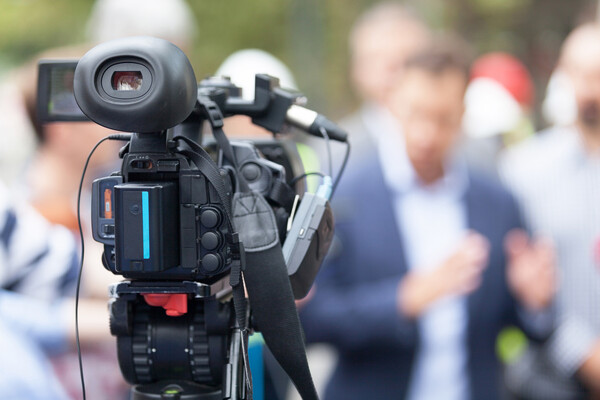 TV camera in front of a crowd of people.