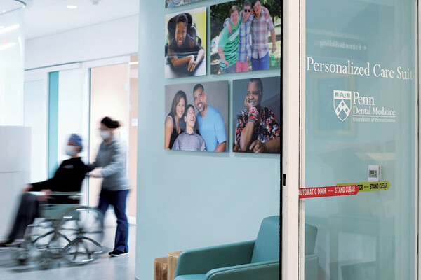 Dental patient in a wheelchair being pushed into the Penn Dental Medicine Personalized Care Suite.