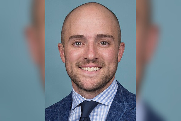 A headshot of men's squash coah Gilly Lane wearing a blue shirt, tie, and jacket.