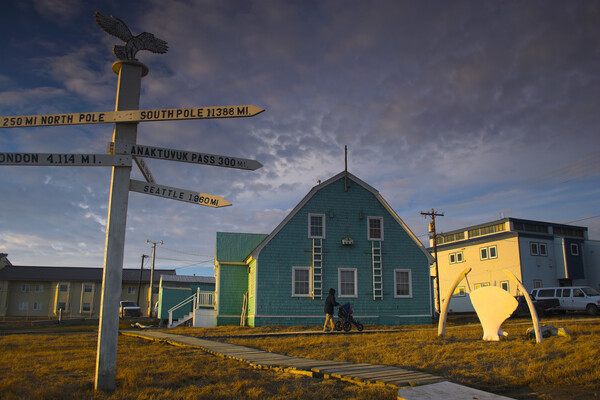 Signpost outside of a building in Alaska indicating distance in miles to global cities.