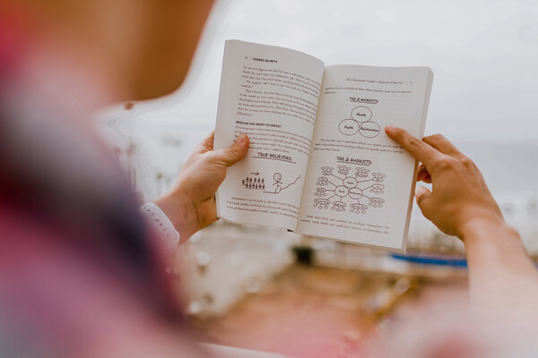 Person reading success story how-to book.