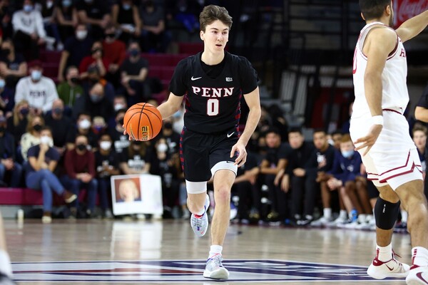 Clark Slajchert, a guard on the men's basketball team, dribbles the ball up the court, wearing a black Penn jersey.