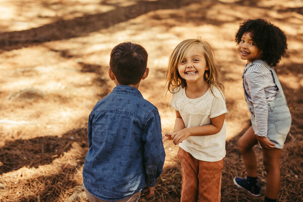 Three children playing outside in the sunshine.