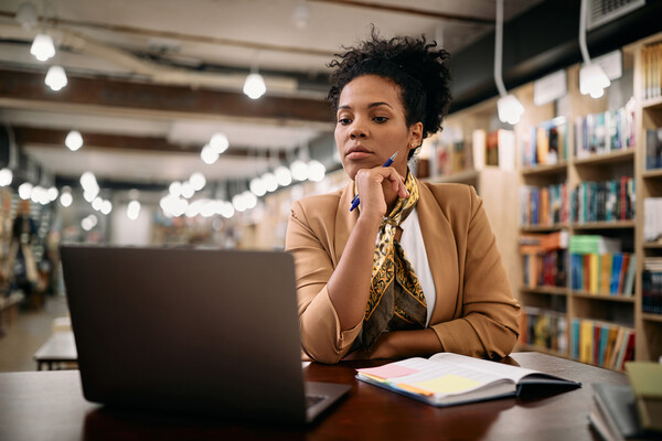 Person sitting in a library looking at a laptop.