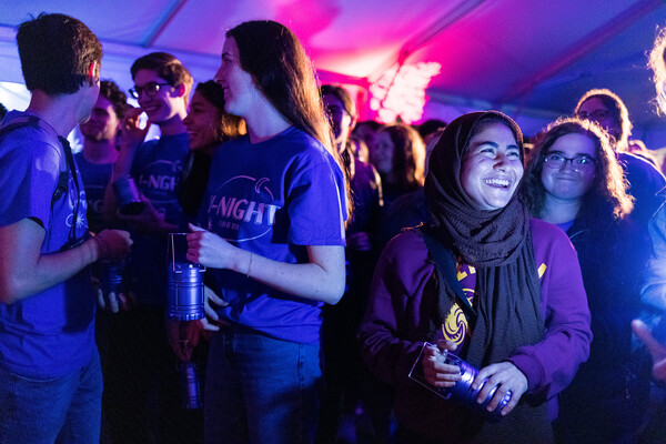 A group of students in a large tent, smiling.