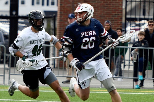 Sam Handley, playing against Dartmouth, makes a move with his stick while an opposing player trails him.