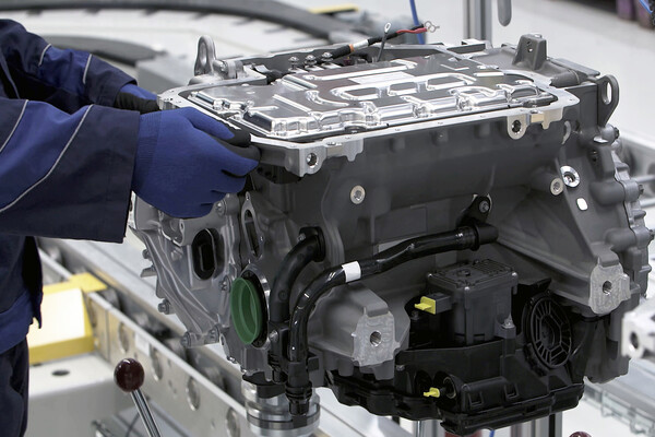 Gloved hands in a car factory working on an electric vehicle motor.