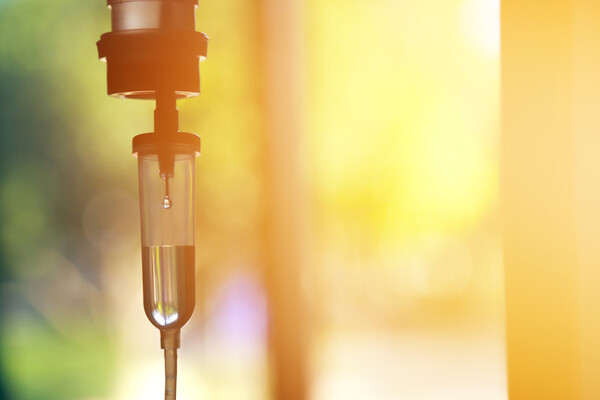 A chemotherapy drip solution hanging by a sunlit window.