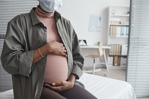 Pregnant person in doctor's office holding belly