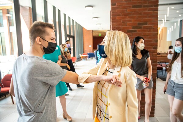Amy Gutmann bumps elbows with a student at Gutmann College House.