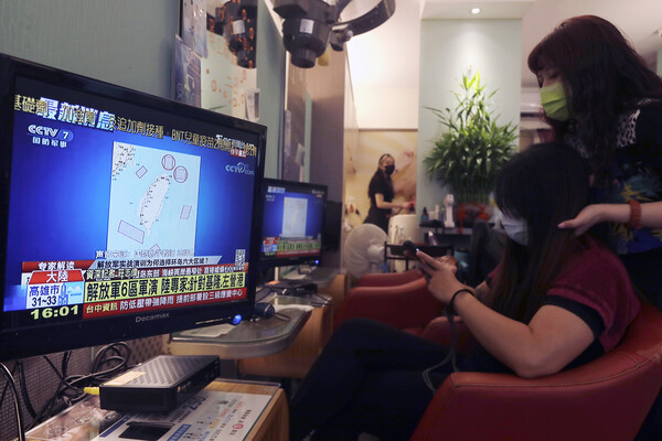 A woman gets her head massaged while watching a news channel