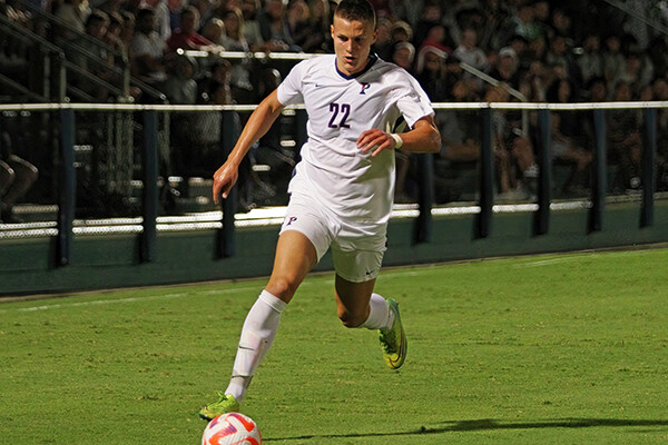 Wearing his white Penn jersey, Stas Korzeniowski of the men's soccer team ticks the ball down the field.