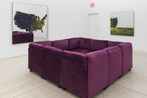 An exhibition by Ken Lum of a purple couch with four sides and two prints hanging on the wall.