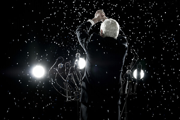 Back of a person in a suit in front of a podium raising their hands in victory in the snow.