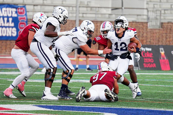 During the Homecoming game versus Yale at Franklin Field, defensive lineman Joey Slackman grabs the Yale quarterback by the ankles and brings him to the ground.