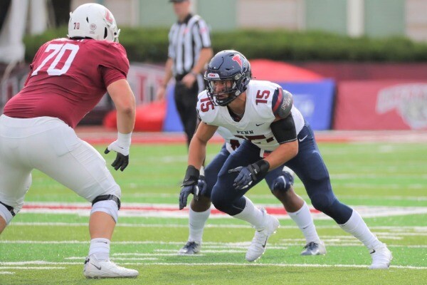 Wearing his white Penn jersey, Jake Heimlicher prepares to engage with an offensive lineman during a game.