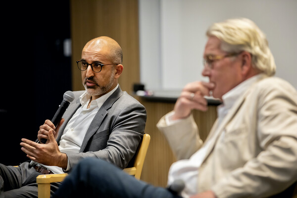 Middle East Center Director John Ghazvinian speaks into a microphone, sitting next to Tor Wennesland