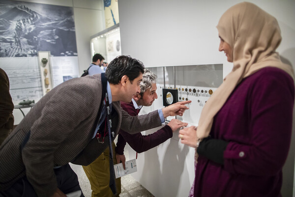 People gathered around artifacts pointing