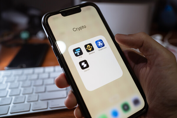 A hand holding a smartphone with a cryptocurrency app open.